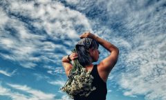 a woman holding a bunch of flowers on top of her head