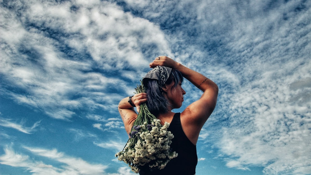 a woman holding a bunch of flowers on top of her head